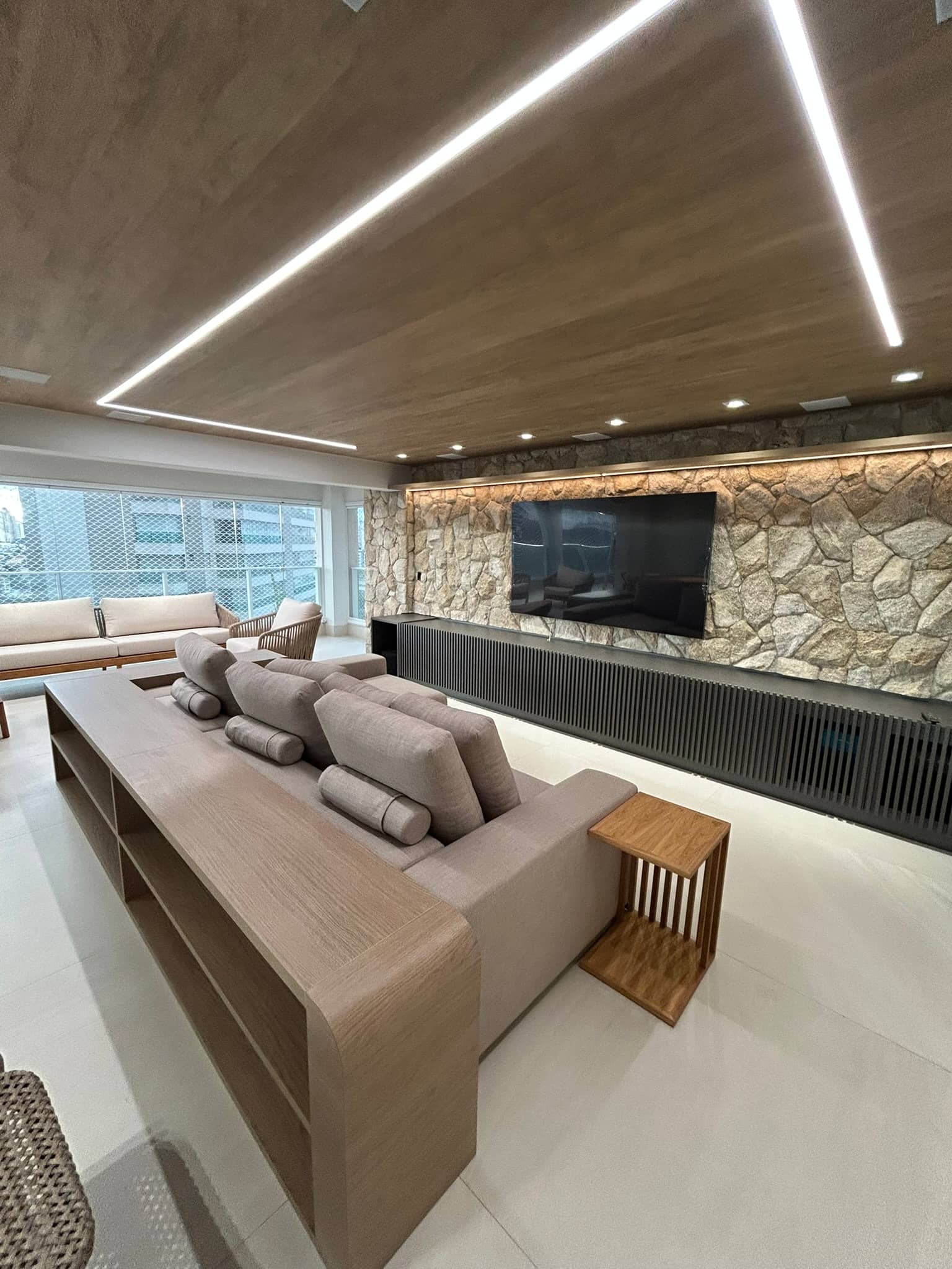 Sala de apartamento de alto padrão com parede de pedra e forro de madeira
